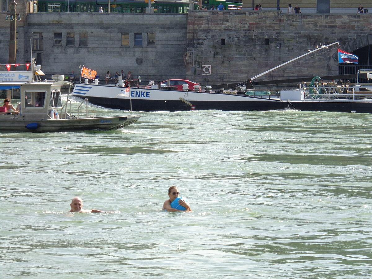 Schwimmerin mit bunten Wickelfischen treibt den Rhein hinunter